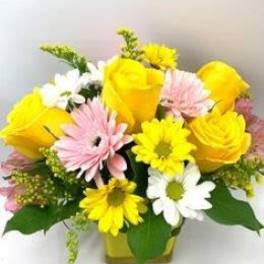 Yellow roses and pink, white, and yellow daisies in a vase