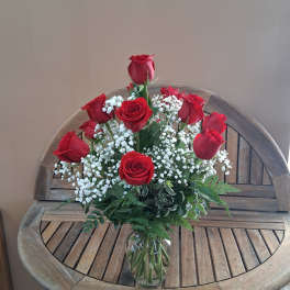 Red roses arranged in a clear glass vase with white baby's breath