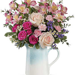Pink and cream roses with alstroemeria in a blue ceramic pitcher
