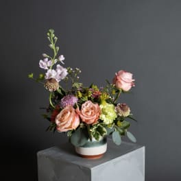 Mixed bouquet of peach and pink roses in a ceramic vase