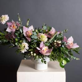 Pink orchid and mixed flower arrangement in a white vase