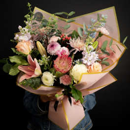 Mixed bouquet of pink, peach, and white flowers wrapped in pink paper