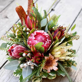 Bouquet of pink protea and mixed greenery on a wooden surface