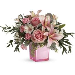 Pink roses and lilies arranged in a pink glass vase