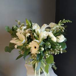 White floral bouquet with lilies, roses, and a gerbera daisy in a glass vase