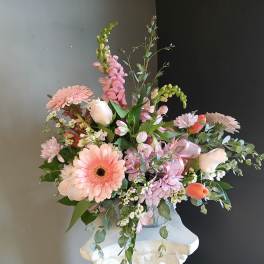 Pink and white mixed flower arrangement in a white pedestal vase