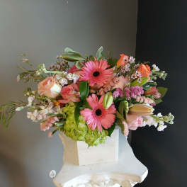 Pink gerbera daisies and roses in a white vase with mixed blooms