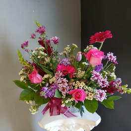Pink and purple mixed bouquet in a clear vase with a ribbon
