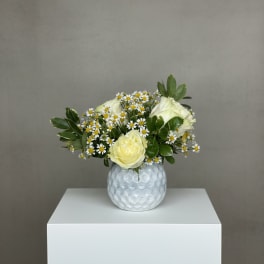 Yellow roses and white daisies in a textured white vase