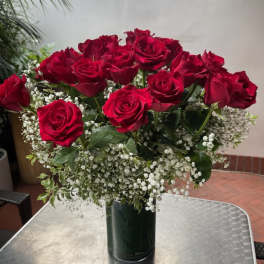 Bouquet of red roses with baby's breath in a dark glass vase