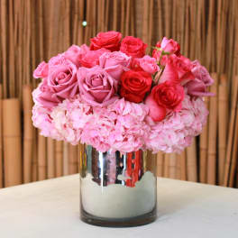 Pink and red roses arranged in a mirrored vase