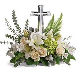 White lilies and cream roses arranged around a silver cross