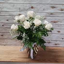 White roses arranged in a glass vase with baby's breath.