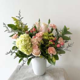 Pink and cream bouquet in a white mug-style vase