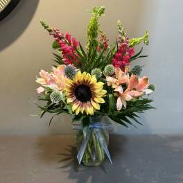 Mixed bouquet in a glass vase with a blue ribbon
