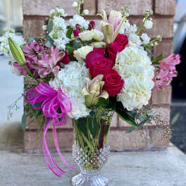 Bouquet of pink roses, white hydrangeas, and lilies in a clear glass vase