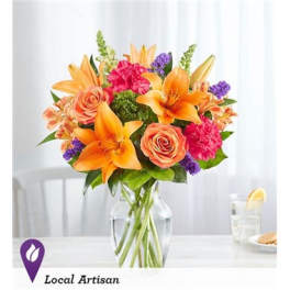 Bouquet of orange lilies, peach roses, and pink carnations in a glass vase