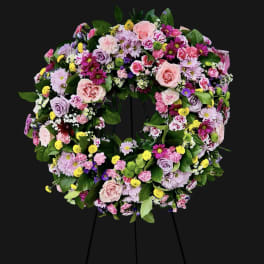 Large floral wreath on a stand with pink, purple, and yellow blooms