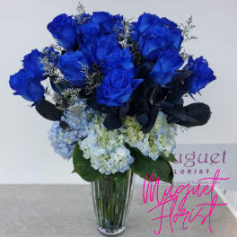Blue roses and pale hydrangeas arranged in a clear glass vase