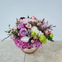 Mixed pink and purple flower arrangement in a round metallic vase
