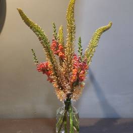 Tall mixed flower arrangement in a clear glass vase