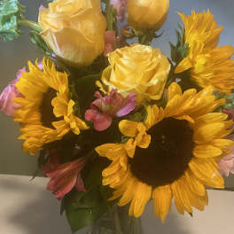 Bouquet of yellow roses and sunflowers in a glass vase