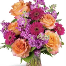 Orange roses and magenta gerbera daisies in a glass vase