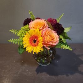 Bouquet of peach roses and a yellow gerbera daisy in a glass vase