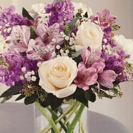 Bouquet of white roses and pink-purple flowers in a glass vase