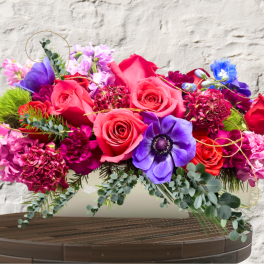Bright mixed bouquet with pink and purple flowers in a low container