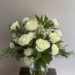 White roses and carnations arranged in a clear glass vase