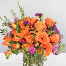 Orange flowers in a clear glass vase with purple accents