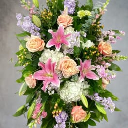 Standing floral spray with pink lilies, peach roses, and lavender blooms