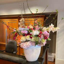 Large mixed floral arrangement in a white vase with tall branches