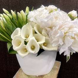 White calla lilies and peonies in a white vase