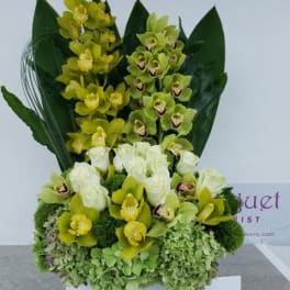Yellow and green orchid arrangement with white roses in a box