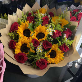 Bouquet of red roses and yellow sunflowers wrapped in tan paper