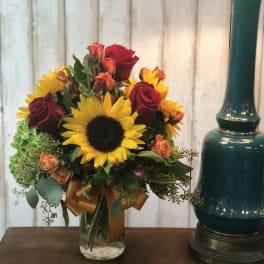 Bouquet of sunflowers and red roses in a glass vase