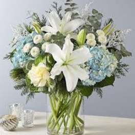 White lilies and blue hydrangeas in a clear glass vase