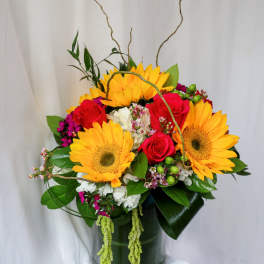 Bright bouquet of sunflowers and red roses in a glass vase