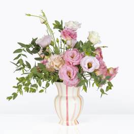 Pink and white lisianthus arranged in a striped vase