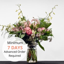 Pink and white mixed bouquet with orchids in a clear glass jar vase