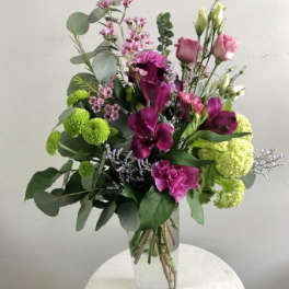 Tall bouquet of purple and pink flowers in a clear glass vase