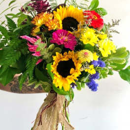 Hand-tied bouquet with bright yellow sunflowers, mixed colorful blooms, and burlap wrap