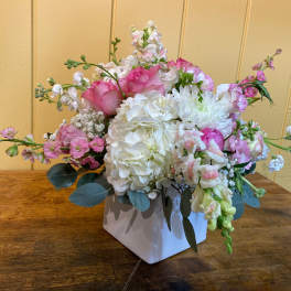 Pink and white floral arrangement in a white square vase