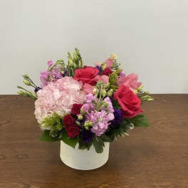 Pink and red flower arrangement in a white box vase
