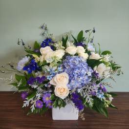 Blue and white floral arrangement in a white vase