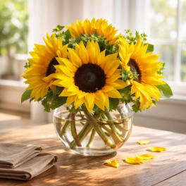 Sunflower bouquet in a clear glass vase on a wooden table