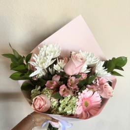 Pink and white bouquet with roses, daisies, and hydrangeas wrapped in pastel paper