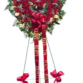 Heart-shaped red rose standing spray with ribbons on an easel